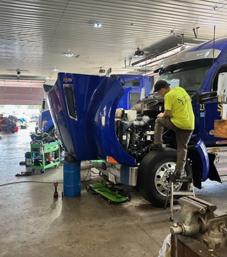A technician servicing a Sturgeon Transport truck in the SWS shop